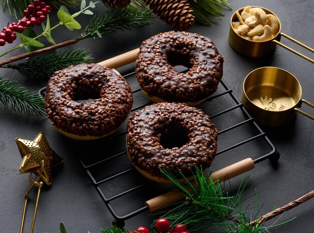 Foto donuts de chocolate salpicados com nozes esmagadas em uma mesa preta