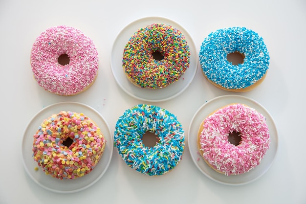 Donuts con decoración colorida sobre fondo de color blanco Vista superior