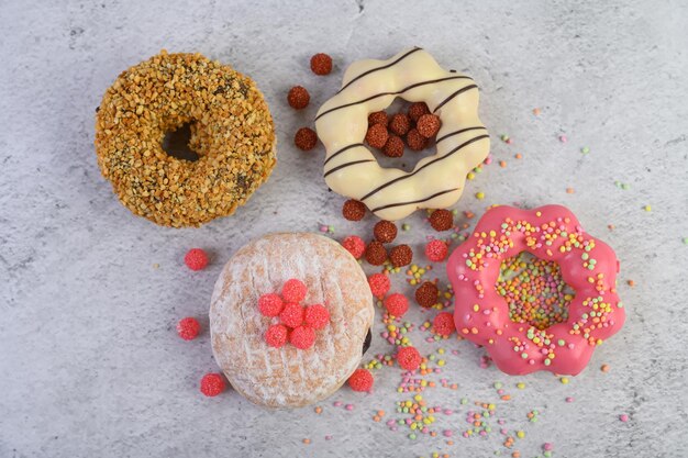 Donuts decorados con glaseado y salpicaduras en fondo blanco vista superior