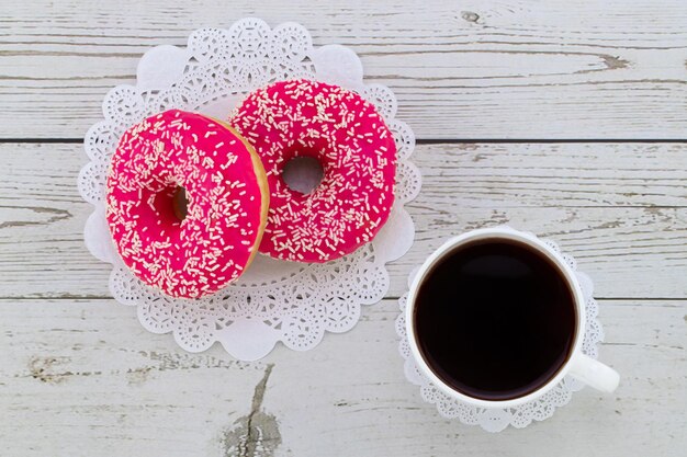 Donuts e café em um fundo branco de madeira, vista superior.