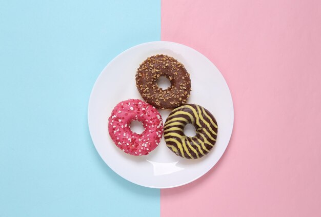 Donuts em um prato em um fundo pastel bluepink Vista superior