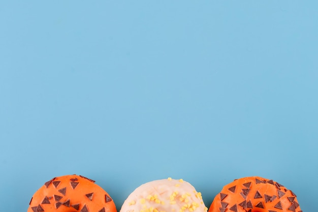 Donuts espolvoreados de naranja y amarillo sobre un fondo azul Espacio de Halloween para texto