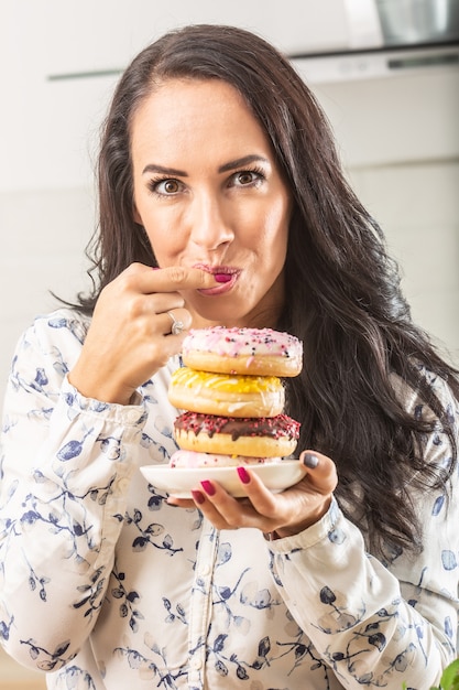 Donuts femininos de degustação de uma seleção em um prato na frente dela.