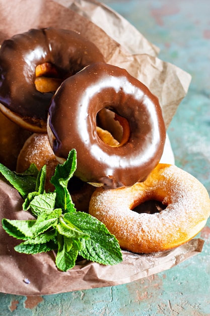 Donuts frescos clássicos com cobertura de açúcar e chocolate com flores de lavanda e folhas de hortelã