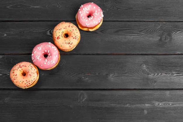 Donuts frescos coloridos en superficie de madera negra oscura