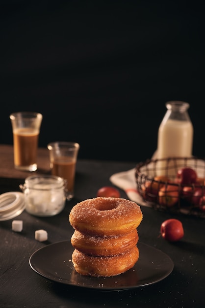 Donuts frescos com açúcar em pó e café com leite em uma mesa de madeira. Café da manhã na aldeia.