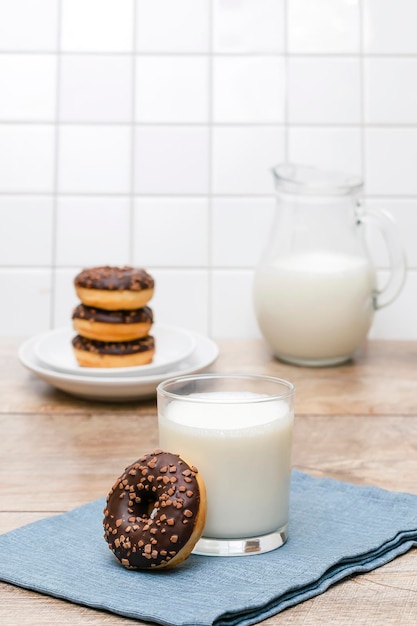 Donuts con glaseado de chocolate con jarra de botella vaso de leche sabrosos donuts dulces de azúcar comida de postre