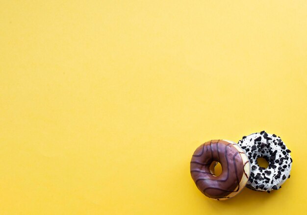 Donuts con gotas de chocolate sobre un fondo amarillo Lugar para inscripciones