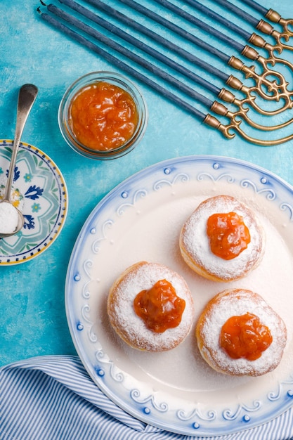 Donuts con mermelada en un plato y Hanukkah en una mesa turquesa