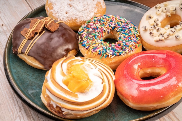 Donuts mezclados sabor original mermelada de chocolate y coberturas de fantasía sobre fondo de madera