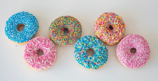 Donuts mit bunter Dekoration auf weißem Farbhintergrund Draufsicht