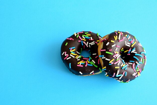 Donuts mit Schokoladenglasur isoliert auf blauem Hintergrund, Nahaufnahme