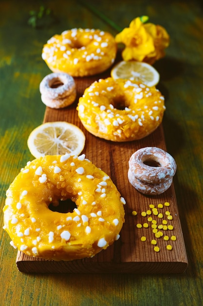 Donuts mit Zuckerglasur und Zitrone auf Holzhintergrund.