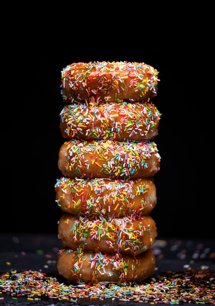 Donuts de montaña con sirope de fresa y cobertura de color sobre un espacio negro