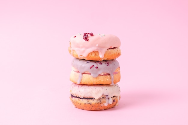 Foto donuts con pila de glaseado pastel aislado sobre fondo rosa claro