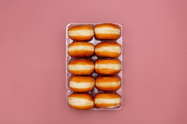 Donuts polacos tradicionales en una caja sobre fondo rosa