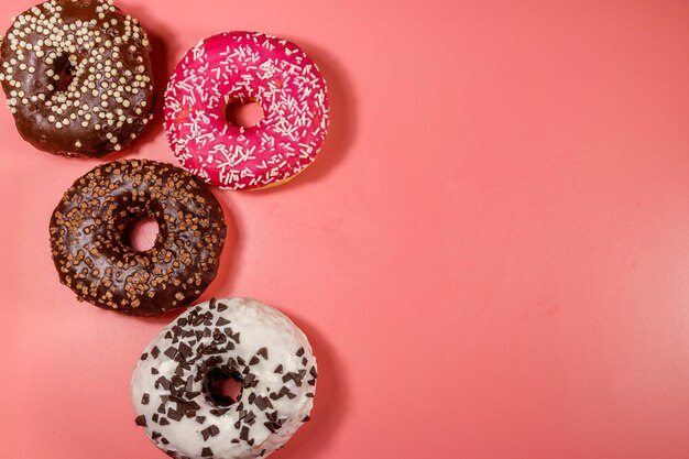 Donuts saborosos no espaço de cópia de vista superior de fundo rosa