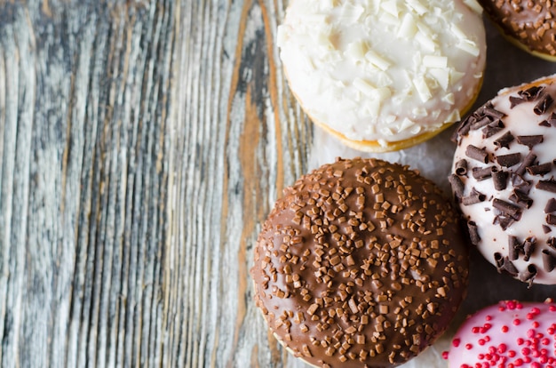 Donuts surtidos con chocolate glaseado sobre superficie de madera