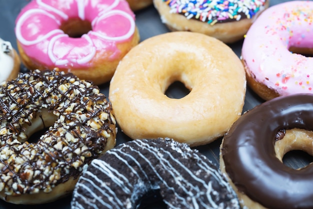 Donuts variados com cobertura de chocolate, rosquinhas com cobertura rosa e granulado