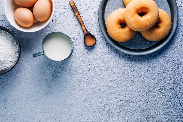 Donuts vitrificados caseiros em fundo colorido. Ingredientes, leite, ovo, farinha. Copyspace