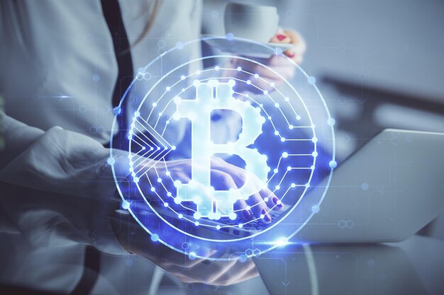 Doppelbelichtung von Frauenhänden, die am Computer tippen, und Hologramm zum Thema Kryptomarkt, das Blockchain-Konzept zeichnet