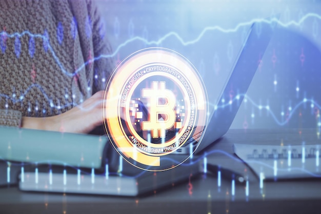 Doppelbelichtung von Frauenhänden, die am Computer tippen, und Hologramm zum Thema Kryptomarkt, das Blockchain-Konzept zeichnet