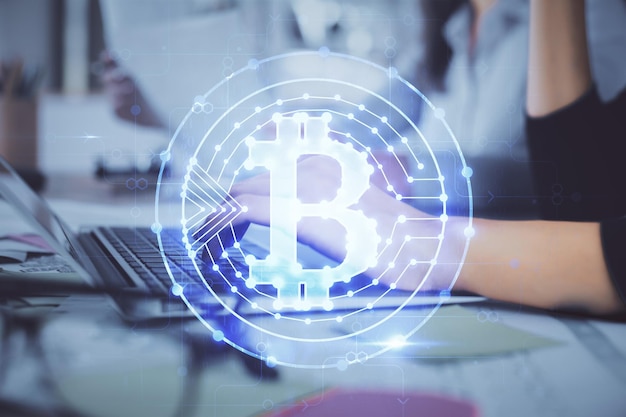 Doppelbelichtung von Frauenhänden, die am Computer tippen, und Hologramm zum Thema Kryptomarkt, das Blockchain-Konzept zeichnet