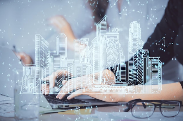 Doppelbelichtung von Frauenhänden, die am Computer tippen, und von Gebäuden, die das Smartcity-Konzept zeichnen