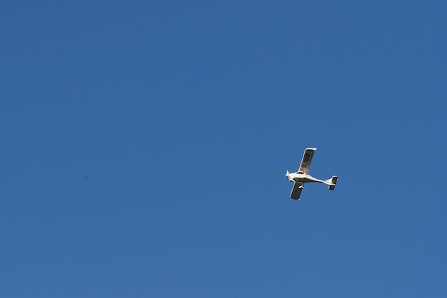 Doppeldecker fliegt hoch im blauen Himmel am sonnigen Tag.