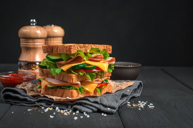 Doppelsandwich mit Schinkenkäse und frischem Gemüse auf schwarzem Hintergrund