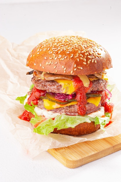 Doppelter Cheeseburger auf weißem Hintergrund und hölzernem Schreibtisch