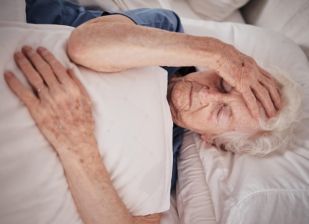 Dor de cabeça e mulher idosa na cama para reabilitação de recuperação de trauma ou descanso em casa de repouso para idosos Problema de saúde Crise de emergência médica e paciente de aposentadoria com câncer cerebral