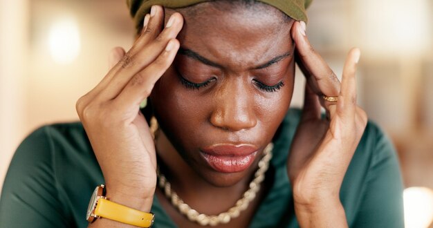 Dor de cabeça estresse e esgotamento com uma mulher negra de negócios sofrendo de tensão enquanto trabalha em seu escritório ansiedade saúde mental e dor com uma empregada esfregando suas tempas em desconforto