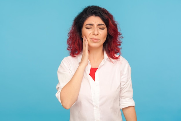 Dor de dente Retrato de mulher doente chateada com cabelo ruivo chique sentindo dor aguda na boca sofrendo problemas dentários cáries ou doença gengival de cárie dentária tiro de estúdio interior isolado em fundo azul