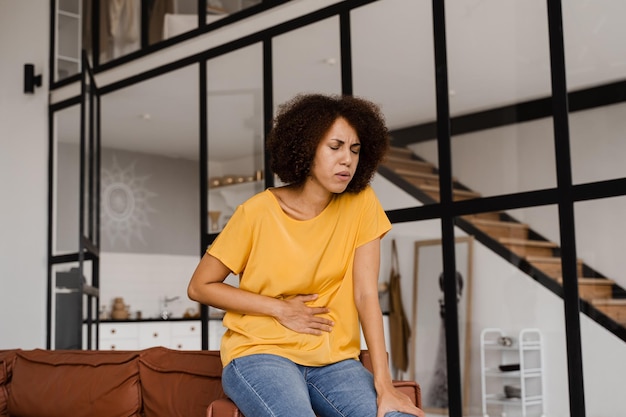 Foto dor de estômago menina afro-americana doente segura o abdômen porque dói pancreatite a doença do pâncreas fica inflamada