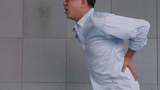 Foto dor nas costas do velho asiático depois de levantar objeto pesado