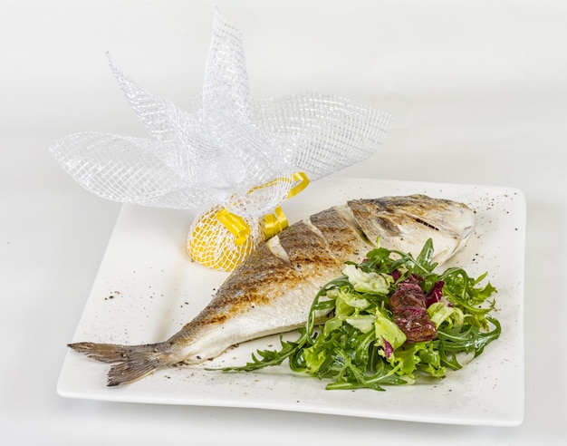 Dorada-Fisch mit Salat auf der weißen Platte Studioaufnahme