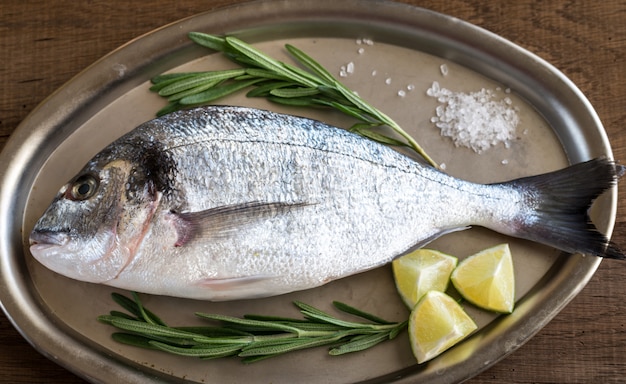 Dorada fresca con ingredientes en la bandeja vintage