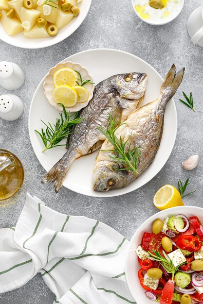 Dorada peixe pargo assado salada grega de legumes frescos batatas cozidas com alho e azeitonas e molho tzatziki Comida saudável Dieta mediterrânea