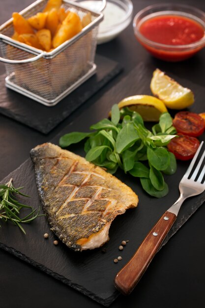 Dorado al horno con ensalada fresca y verduras. Orientación vertical