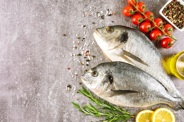 Dorado de peixe fresco de frutos do mar e ingredientes para cozinhar em fundo cinza vista superior com espaço de cópia