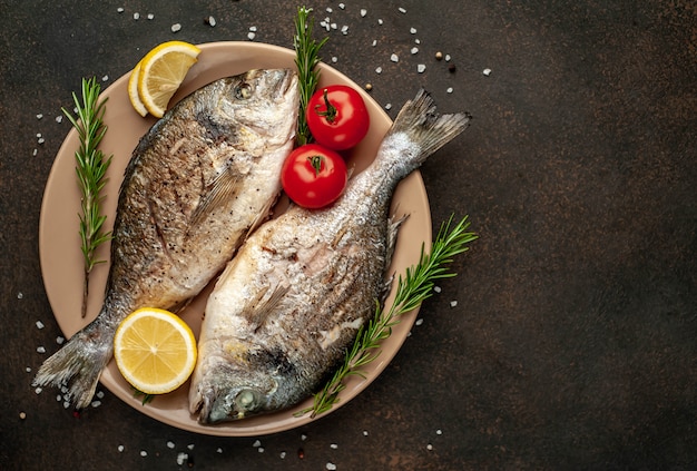 dorado dorado a la parrilla y papas fritas en un plato con especias y limón sobre un fondo de piedra con espacio de copia para su texto