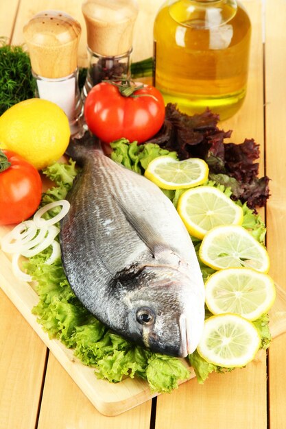 Foto dorado fresco na tábua com limão e legumes na mesa de madeira