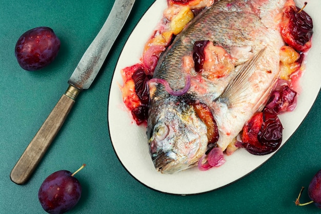 Dorado ou peixe dourado assado com ameixas Gilthead peixes em um prato branco