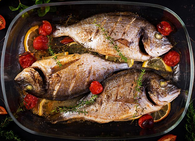 Dorado de pescado al horno con limón y hierbas en una bandeja para hornear