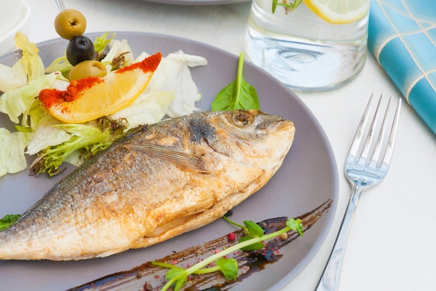 Foto dorado a la plancha con lechuga, limón y aceitunas