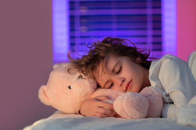 Dormir de noche niño lindo durmiendo con un oso de peluche de juguete en la cama en casa hora de acostarse niño duerme niño dormido o