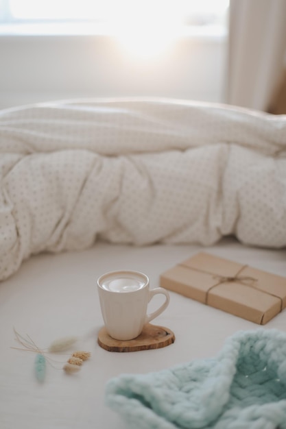 Dormitorio acogedor y luminoso Taza de café aromático y manta cálida en la cama con una manta suave en el interior vista superior