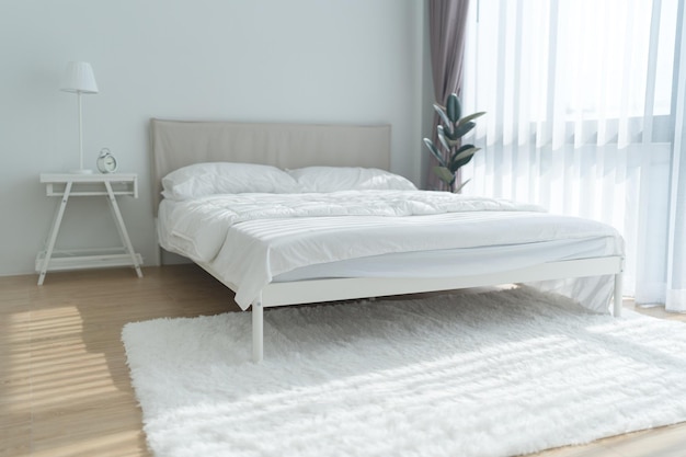 Dormitorio blanco con cortinas blancas y almohadas blancas.