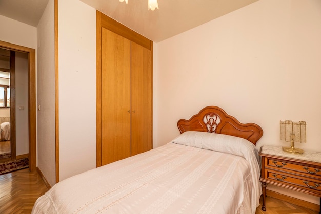 Dormitorio con cama de matrimonio con cabecera de madera pegajosa en una habitación con suelo de roble y armario empotrado con puertas de madera